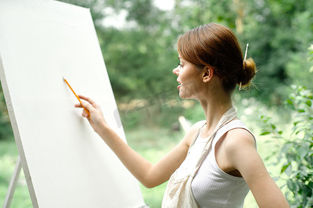 大自然中的艺术家用铅笔在画架上作画