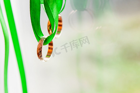 金色的结婚戒指装饰在明亮的绿色丝带上。
