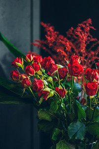 婚礼庆贺摄影照片_深色背景上有红玫瑰花束的静物画