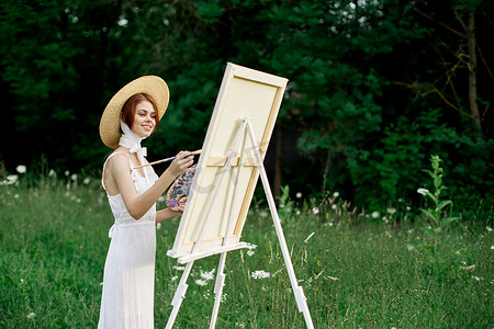 穿着白色连衣裙的漂亮女人在户外绘画艺术创意