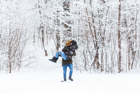 热恋中的年轻情侣在白雪皑皑的森林里玩得很开心。