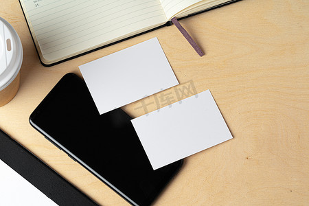 名族名片摄影照片_桌上空白名片和黑色智能手机屏幕的模型