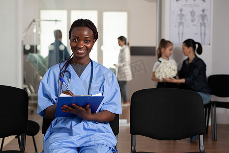 黑暗房间摄影照片_医院等候区椅子上坐着非洲裔美国护士的肖像