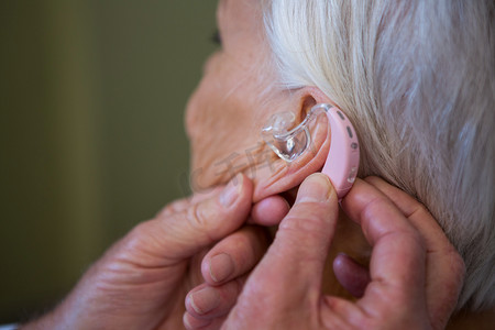 医生在老年患者耳朵中插入助听器