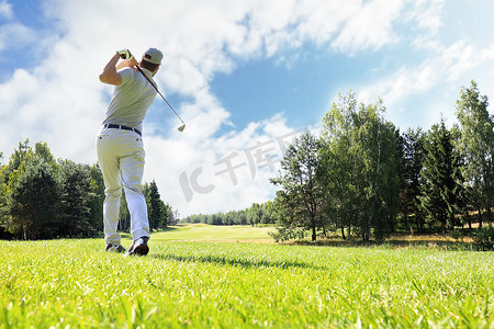 高尔夫上杆摄影照片_高尔夫球手在暑假期间在球场上用球杆击球。