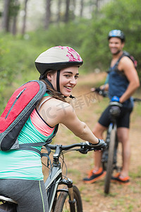 森林骑车摄影照片_快乐的女骑车人和男人在土路上