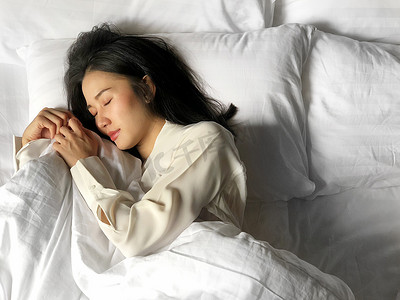 盖被子的猪摄影照片_睡在床上的美丽的亚洲女人在白色被子下睡觉