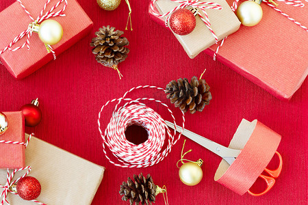包装礼品摄影照片_为假期做准备-用红色和米色包装纸包装礼品