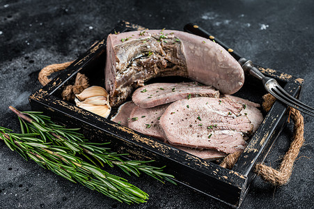 红烧小羊肉摄影照片_煮熟的煮小牛肉或牛舌切片放在木托盘中。