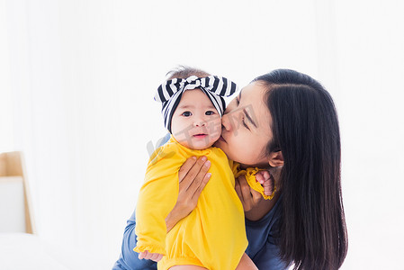 儿童天安门摄影照片_母亲在白色床上亲吻她的婴儿