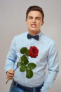 浪漫系摄影照片_浪漫的男人，一朵红玫瑰，穿着蓝色衬衫，脖子上系着领结，灰色背景