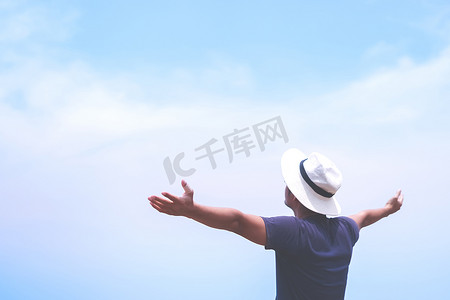 男人举起手来迎接蓝天和夏日海滩背景的天空自由概念。