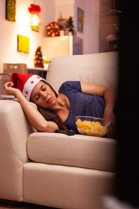 看完摄影照片_看完冬季娱乐电影后，戴着圣诞帽的女人睡在沙发上