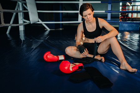 坐在拳击场训练后戴红手套的女拳击手的肖像