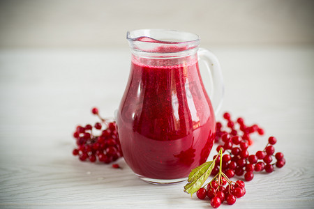 榨摄影照片_鲜榨的浓稠天然果汁，带有来自成熟红色荚莲属植物的果肉，装在醒酒器中