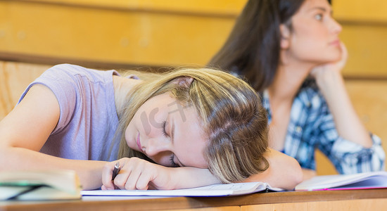 无聊的学生在同学睡觉时听