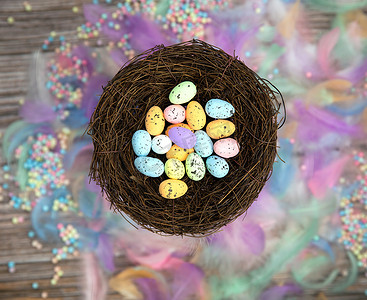 鸟巢中色彩缤纷的复活节彩蛋，周围环绕着柔和的彩色羽毛和木制立方体，上面写着“复活节快乐顶视图”，现代背景设计，复活节假期，春天，概念