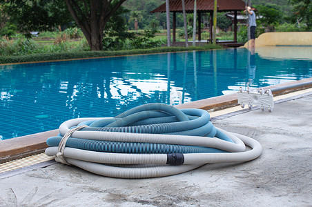 水泥地板上的游泳池真空吸尘器软管，清洁水池的手动设备。