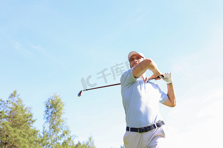 高尔夫球手在暑假期间在球场上用球杆击球。