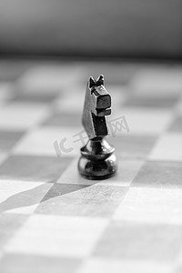国际象棋骑士摄影照片_国际象棋骑士棋子在棋盘上关闭。
