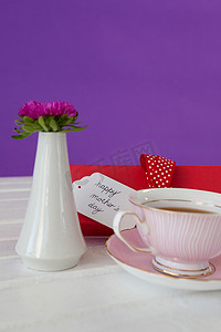 木表面上的红茶、花瓶和愉快的母亲节卡片