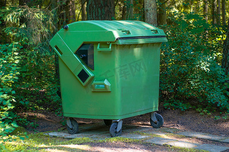 绿色大气摄影照片_有生活垃圾的绿色容器反对绿色木头
