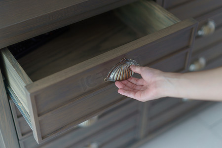 手打开棕色木制文件柜抽屉。