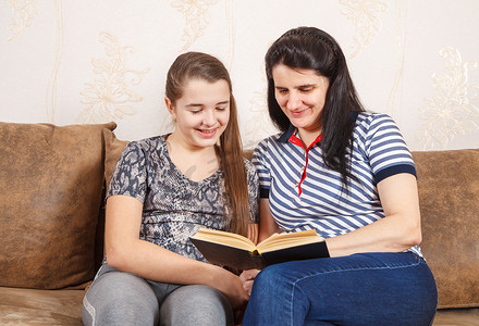 小孩儿看书摄影照片_妈妈和女儿坐在沙发上看书