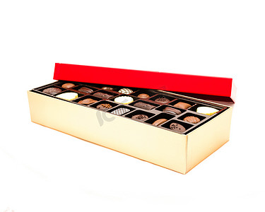 彩带装饰摄影照片_特写部分打开的巧克力盒，上面有喜庆的红盖和各种松露