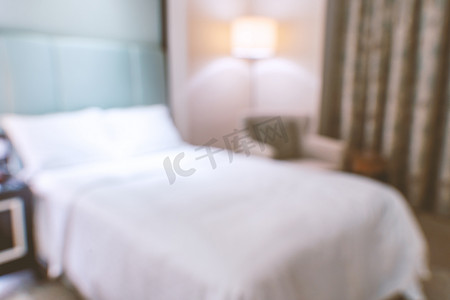 干净舒适的现代酒店卧室内部配有双人床，抽象的散焦模糊与散景背景，豪华旅行的设计理念。