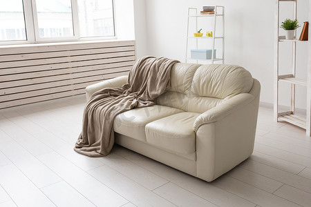 米色沙发靠在简单的客厅内部的白色空墙上。