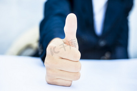 拇指手势摄影照片_关闭商人的手竖起大拇指或通过在白色上隔离的手势显示幸福。