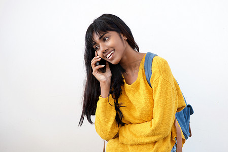 印度女性摄影照片_年轻的印度女性在孤立的白色背景下用手机笑着说话