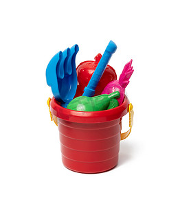 婴儿红色塑料桶，带铲子和玩具隔离在白色背景。