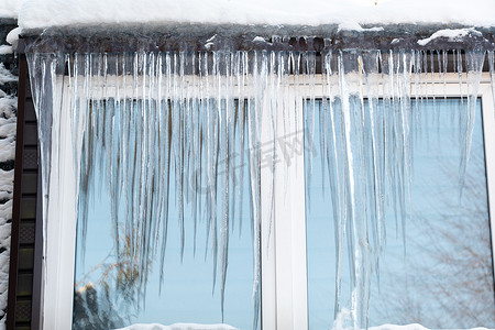 结满了摄影照片_在寒冷的日子里，房子的窗户上结满了冰柱。