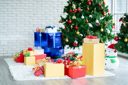 有玻璃窗的房间里设置了一组圣诞节装饰，包括礼物或礼品盒、雪人模型、圣诞树等。