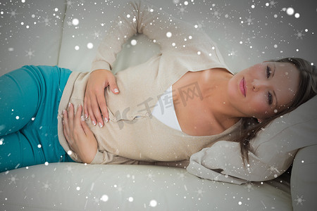 妇女躺在沙发上胃部不适的合成图像