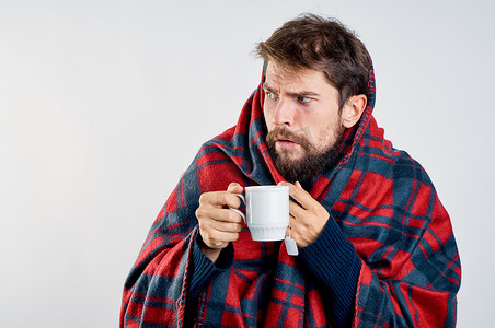 饮料冒气摄影照片_冷男人用毯子暖饮料健康问题