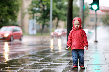 秋天雨天可爱的蹒跚学步的女孩