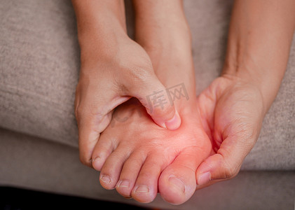 女性握住疼痛的脚并按摩拇囊炎脚趾以缓解疼痛的特写镜头。