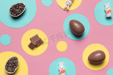 俯视复活节彩蛋兔子巧克力片圆框粉红色背景。