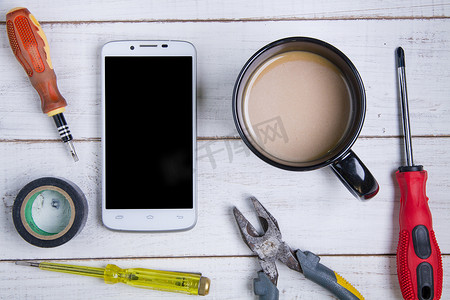 智能手机、咖啡杯和设备修理在白色木头