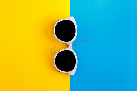 明亮的蓝青色和黄橙色背景上阳光明媚的时尚白色太阳镜，顶视图，孤立。