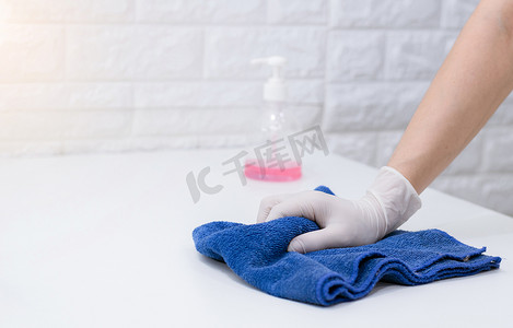 戴手套的妇女擦桌子以清洁灰尘