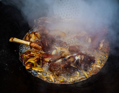 大锅牛肉摄影照片_羊肉在一个大铸铁锅里着火。