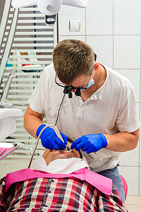 诊所的牙医，牙垢清除程序，双筒望远镜的牙医清除患者口腔中的牙垢。