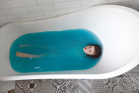 洗眼睛摄影照片_可爱的孩子在浴缸里沐浴在蓝色的水中