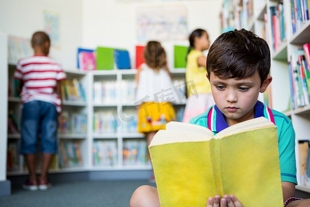 小学男孩在学校图书馆看书