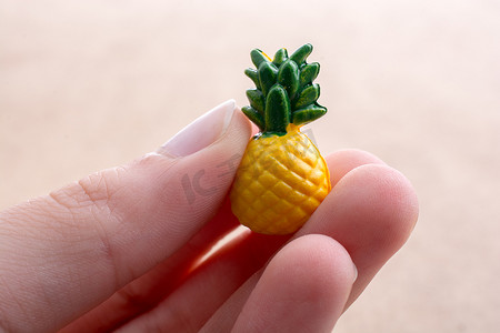 手拿着背景上的小菠萝模型