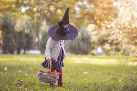 小女巫打扮的女孩在秋天的公园。